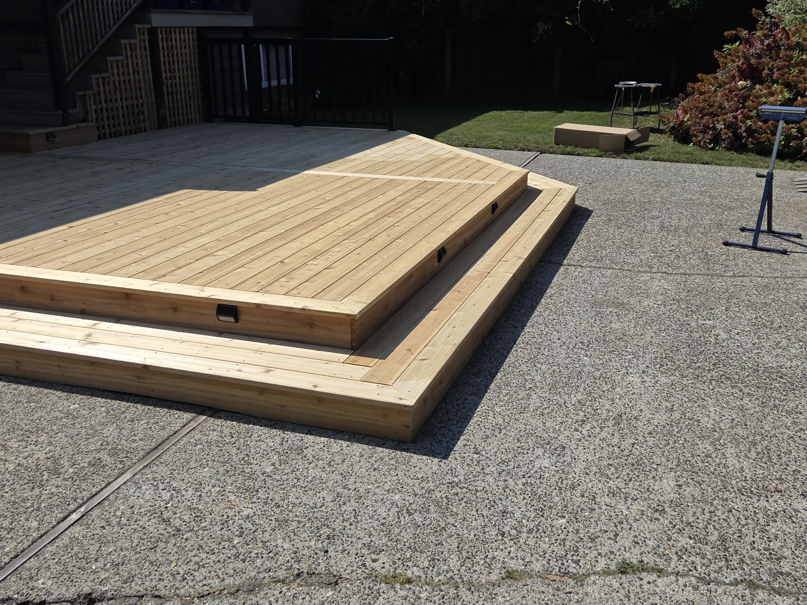 Two level cedar deck on an exposed aggregate patio with built in lights